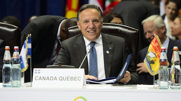 François Legault, assis à une table, lors d'une séance plénière de l'OIF.