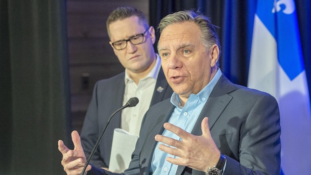 François Legault lève les mains en parlant, tandis que Benoit Charette est derrière lui.