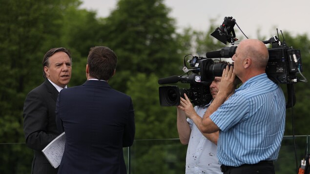 François Legault en entrevue avec Patrice Roy, entourés de 2 caméramans. 
