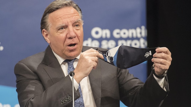 François Legault brandit un masque durant un point de presse.