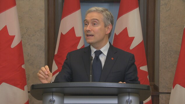 وزير الابتكار والعلوم والصناعة الكندي، فرانسوا فيليب شامبان، يتحدث واقفاً خلف منبر.