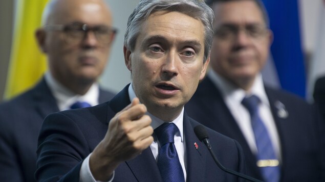 Un homme parle et fait un geste de la main.