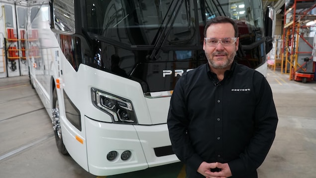 François Tremblay devant un autobus blanc.