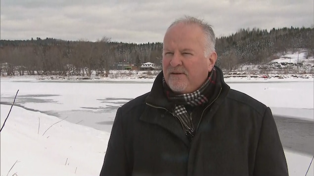 François Veilleux en manteau d'hiver, dehors devant une rivière.