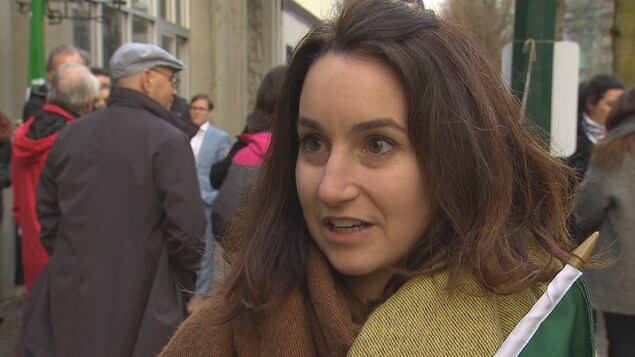 Une jeune femme manifeste dans la rue avec un drapeau franco-ontarien à la main. Une jeune femme manifeste dans la rue avec un drapeau franco-ontarien à la main.