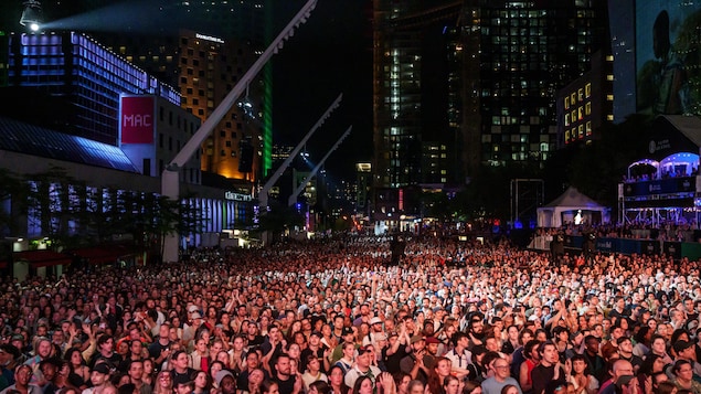 Une foule massée sur la Place des festivals à Montréal assiste à un spectacle.
