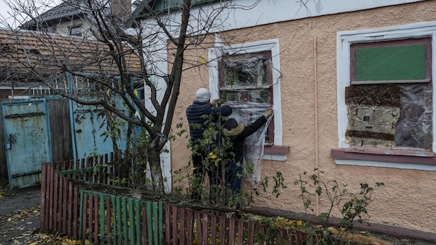 Des habitants de Kherson doublent leurs fenêtres de bâches en plastique.