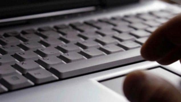 Une main devant un clavier d'ordinateur.