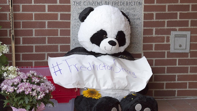 Un panda en peluche et des fleurs devant un poste de police de Fredericton. Un panda en peluche et des fleurs devant un poste de police de Fredericton.