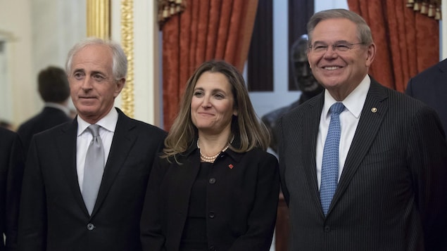 Une femme et deux hommes posent ensemble lors d'un événement officiel. Une femme et deux hommes posent ensemble lors d'un événement officiel.