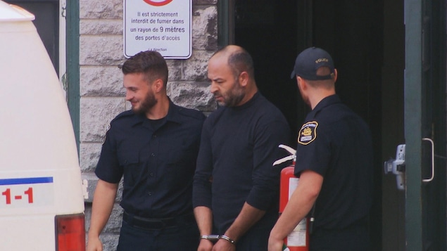 Le suspect, Frej Haj Messaoud, escorté par deux policiers vers un fourgon