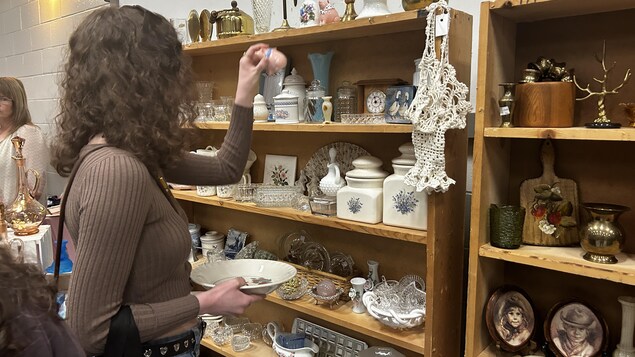 Une femme filmée de dos regarde des articles, le 13 avril 2025 à Winnipeg.