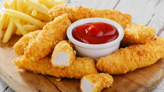 Des frites de poulet pané sur une assiette, accompagnées de ketchup
