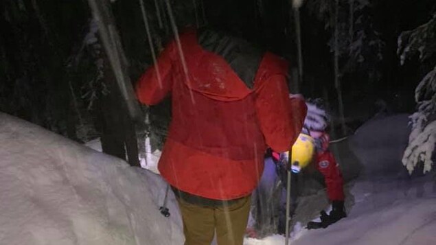 Des membres de l'équipe de recherche et sauvetage marchent dans la neige.