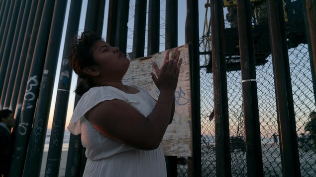 Une femme debout devant la clôture qui sépare le Mexique des États-Unis. Une femme debout devant la clôture qui sépare le Mexique des États-Unis.