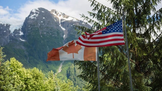 The Canadian and American flags fly side by side.