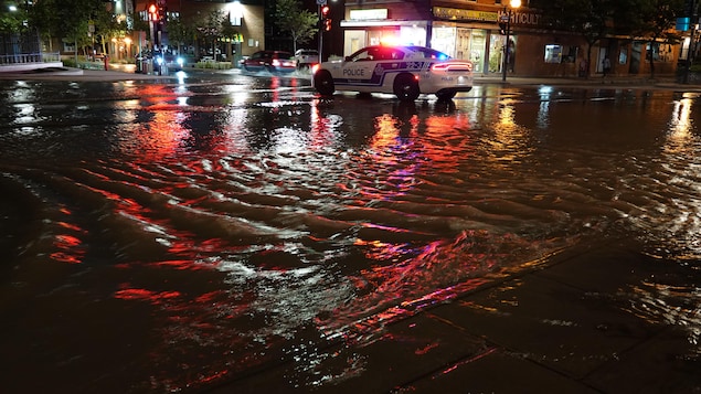 Une rue inondée avec une voiture de police.