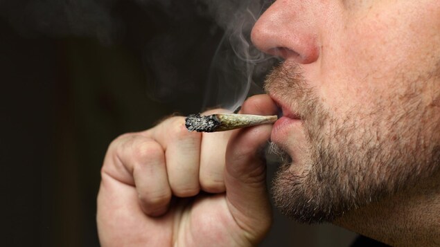 Un homme fume un joint.