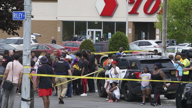Des gens se rassemblent à l'extérieur d'une épicerie de Buffalo où a eu lieu une fusillade samedi après-midi. 