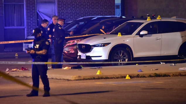 Toronto police are pictured at the scene of a fatal shooting in the parking lot of an Etobicoke high school late Sunday.