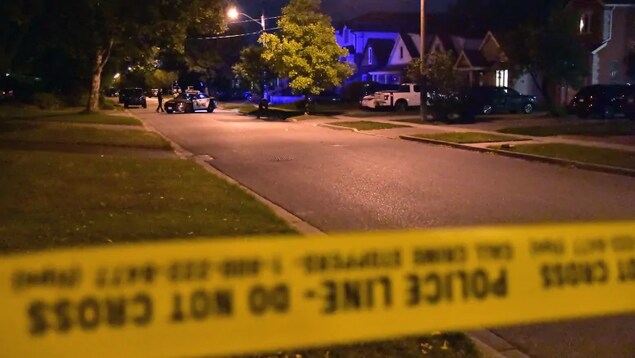 Photo d'une banderole de police jaune bloquant une rue; une autopatrouille est située en arrière-plan.