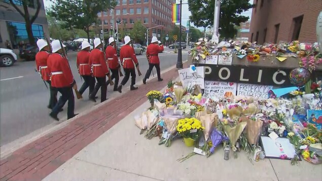 Des agents en uniforme marchent en rang près du mémorial en la mémoire des victimes de la fusillade. Des agents en uniforme marchent en rang près du mémorial en la mémoire des victimes de la fusillade.