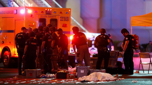 Des policiers et des pompiers rassemblés près du corps d'une victime. Des policiers et des pompiers rassemblés près du corps d'une victime.
