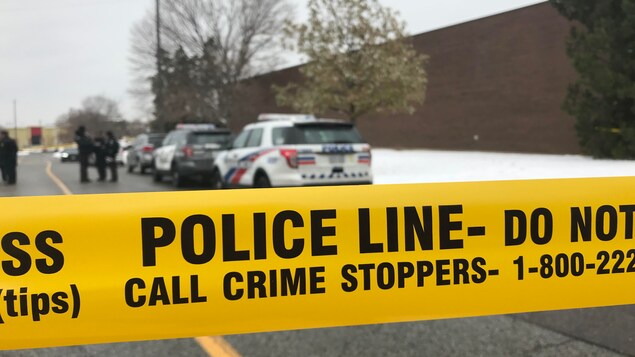 Des voitures de police derrière un ruban de police.