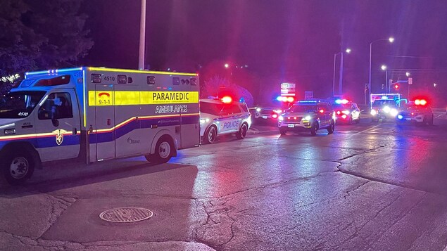 Cinq voitures de police et deux ambulances, avec leurs gyrophares allumés, la nuit.