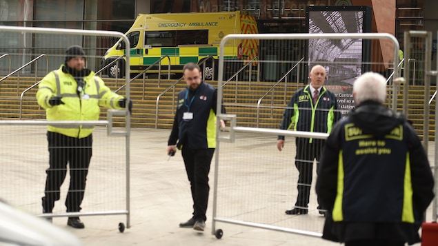 Des hommes installent des barrières métalliques devant le complexe.