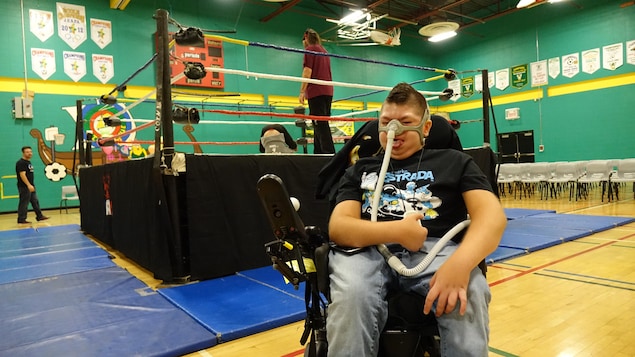 Gabriel pose devant le ring avec une grimace de lutteur et un pouce dans les airs.