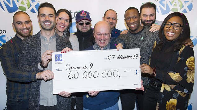 Les gagnants Julie Beland, Haidar Abi Haidar, Robert Macri, Diane Dorele Fossouo Djuidje, Nathaniel Thomas, Darius Hozhabr Zandi, Peter Jewett, Randolph Dandan and Enzo Scattone brandissent leur chèque de 60 millions de dollars.