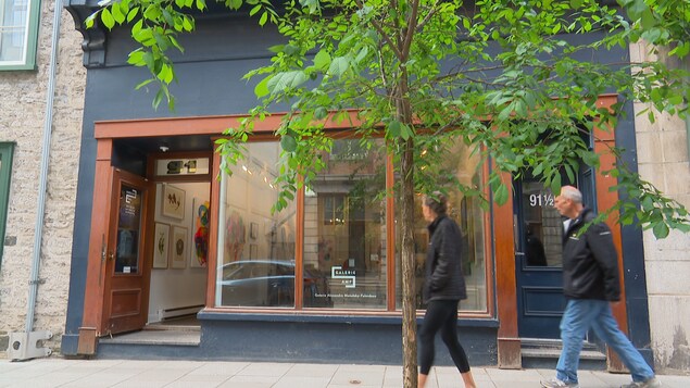Deux passants circulent devant une galerie d'art.