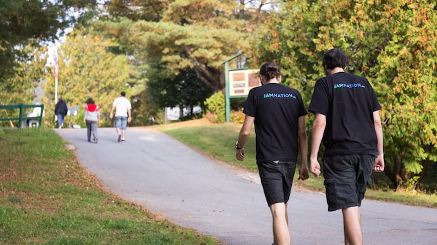 Deux jeunes hommes de dos, se dirigeant vers une petite pente asphaltée.