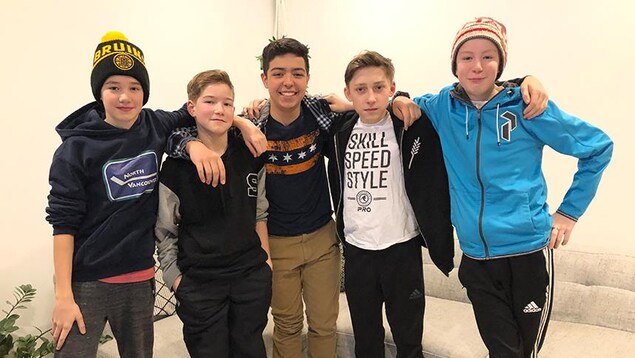 Cinq jeunes garçons sourient pour la caméra.