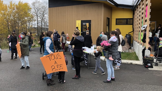 Des parents et des éducatrices manifestent dans la cour d'une garderie.