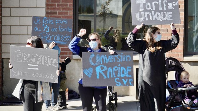 Des éducatrices en grève tiennent des pancartes.