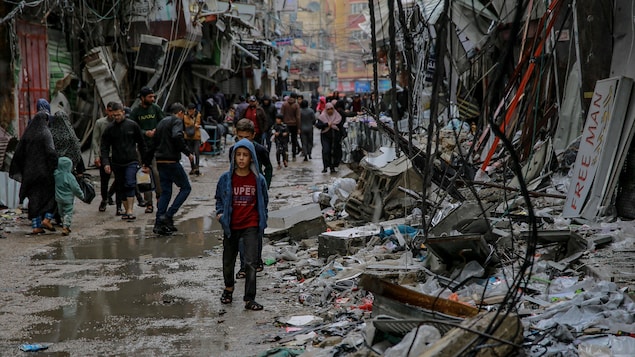 Palestinians walk in the Al-Zawiya market in Gaza, destroyed by Israeli bombing.