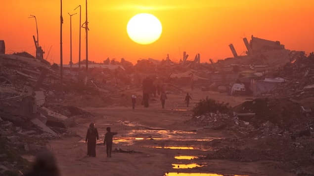 Palestinians walk among destroyed buildings as the sun sets over Gaza City on Jan. 4. The World Bank estimates it will cost $70 billion US to rebuild Gaza, but funds are in limbo.