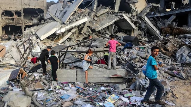 أطفال يبحثون عن أشياء بين المباني التي دمرتها الغارات الجوية الإسرائيلية في خان يونس جنوبي قطاع غزة اليوم.
