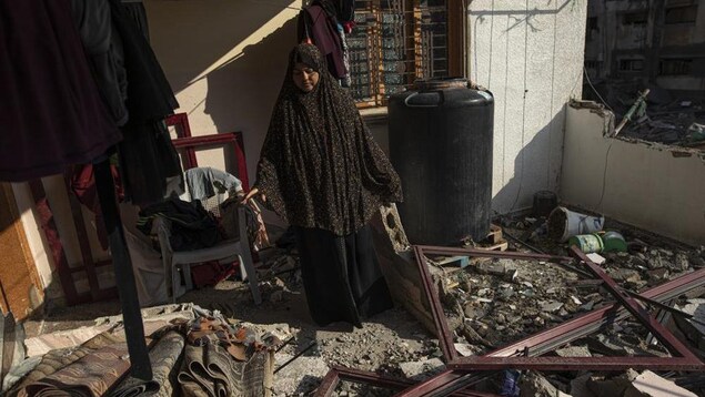 Une Palestinienne constate les dégâts après que sa maison a été touchée par une frappe aérienne israélienne dans la ville de Gaza.