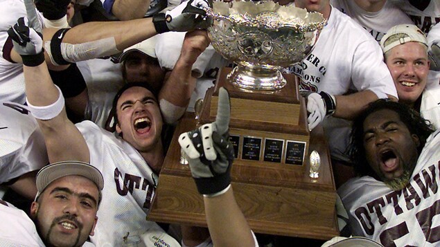 Les joueurs des Gee-Gees fêtent autour de la Coupe Vanier.
