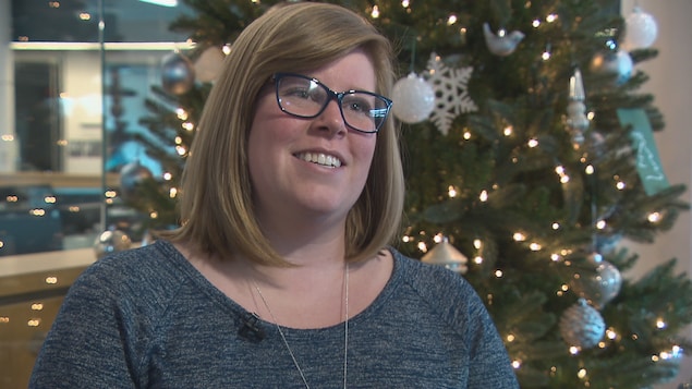 Gena Alderson d'Eco360 se tient devant un sapin de Noël illuminé. Gena Alderson d'Eco360 se tient devant un sapin de Noël illuminé.