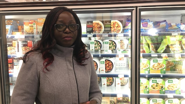 Geneviève M'boua devant un présentoir de produits surgelés.