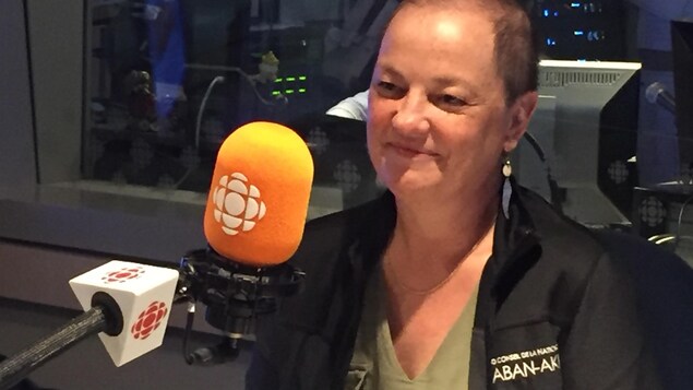 Geneviève Treyvaud, souriante, devant un micro, dans les studios de Radio-Canada Mauricie.