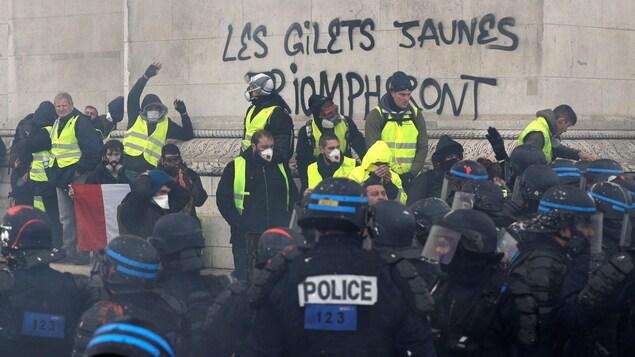 Des manifestants portant des gilets jaunes face aux forces de l'ordre au pied de l`Arc de triomphe Des manifestants portant des gilets jaunes face aux forces de l'ordre au pied de l`Arc de triomphe