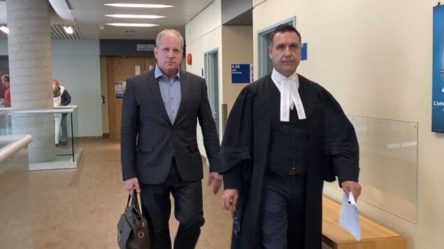 Le docteur vêtu d'un complet tient une mallette à sa main et marche au côté de l'avocat, vêtu de sa toge.