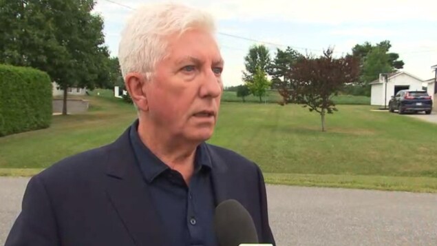 Gilles Duceppe devant un terrain gazonné.