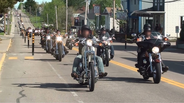 Des motocyclistes, rendus flous, circulent sur une rue principale.