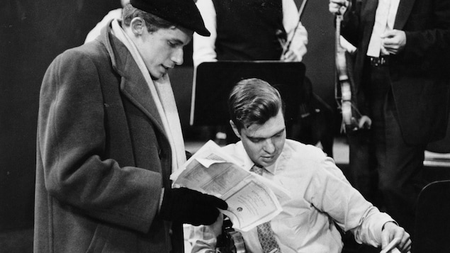 Le pianiste Glenn Gould, debout et le violoniste Calvin Sieb, assis, étudient une partition musicale ensemble pour un enregistrement en 1957.